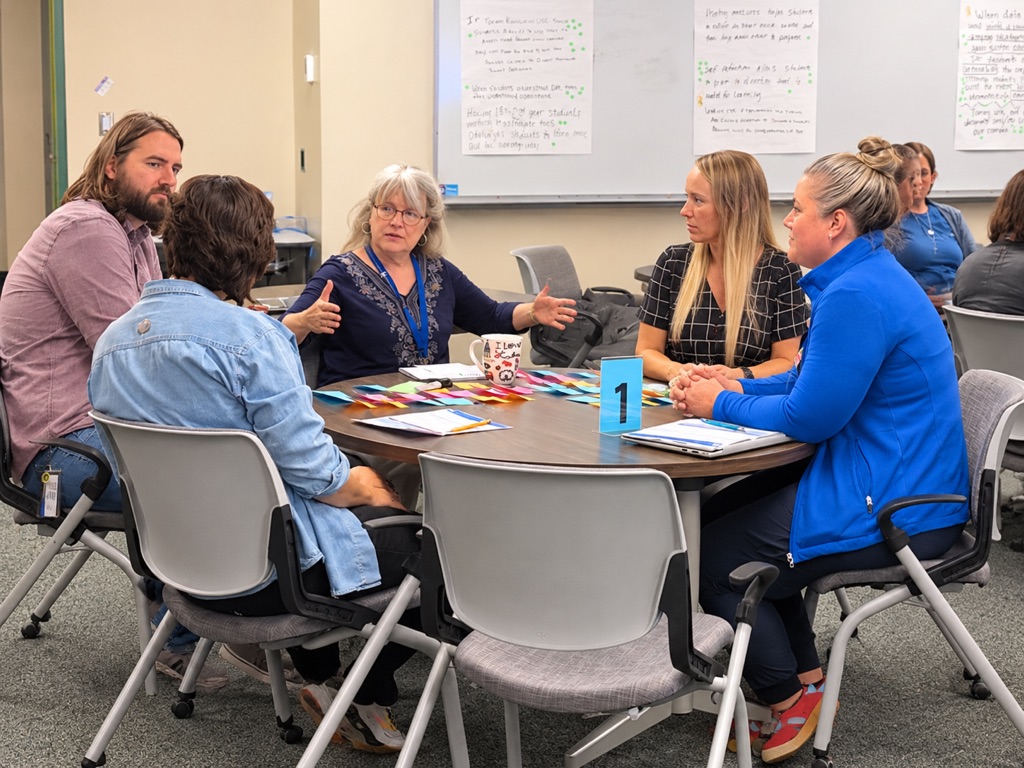 Group of teachers sitting a a round table disucssing