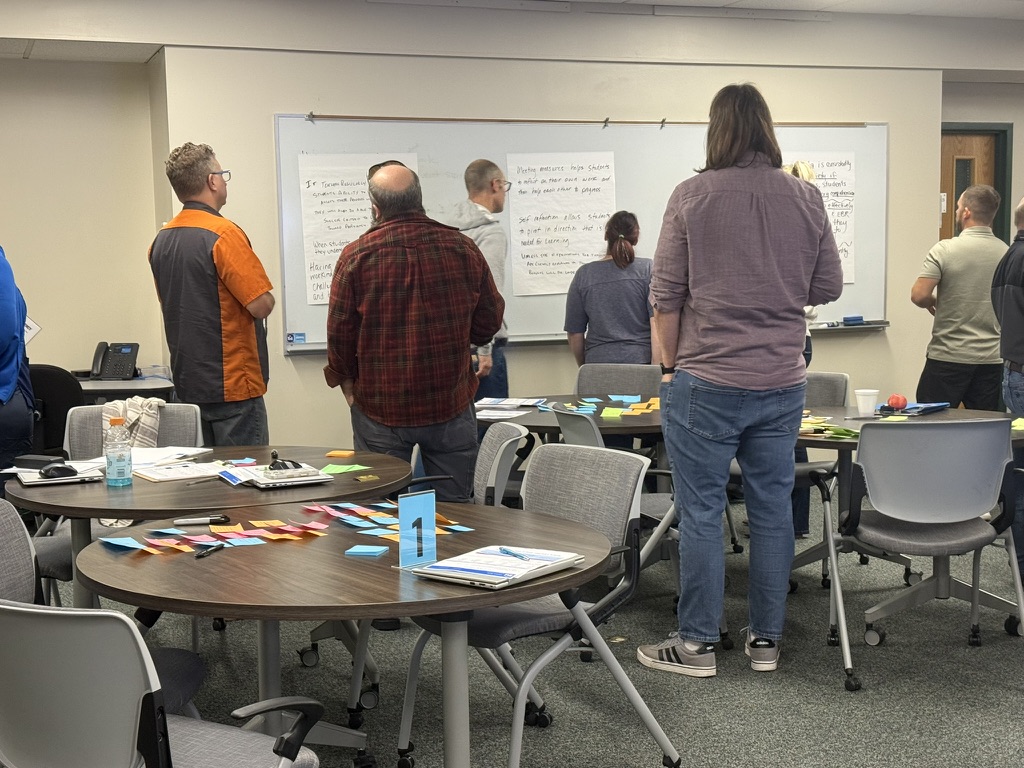 Group of teachers standing and reviewing notes on the wall