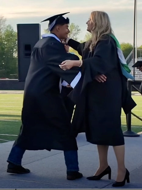 Student hugging an administrator after receiving their diploma