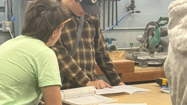 Students in manufacturing class reviewing math concepts at a work table