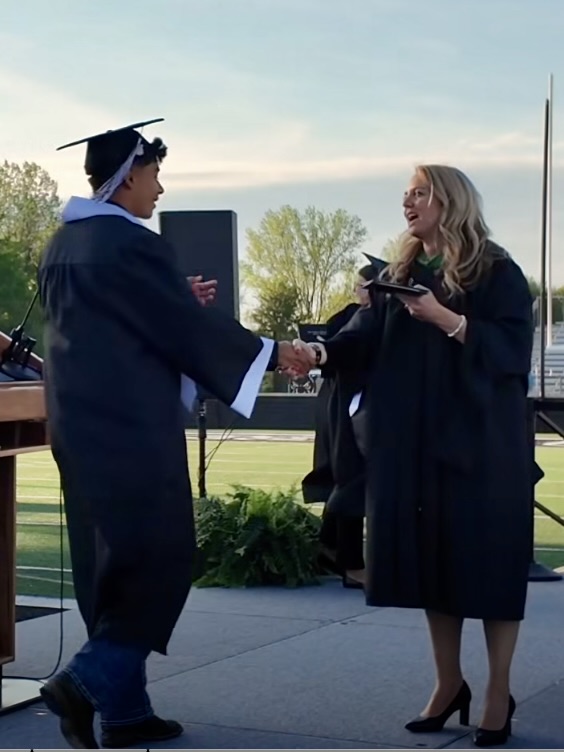Student shaking an administrator's hand as they receive their diploma