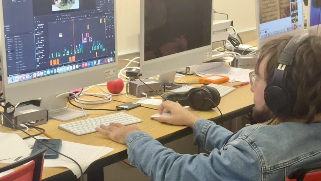 Student sitting at a computer using video editing software