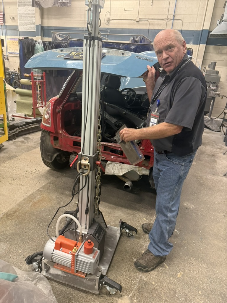 Automotive instructor standing at a vehicle with a piece of equipment