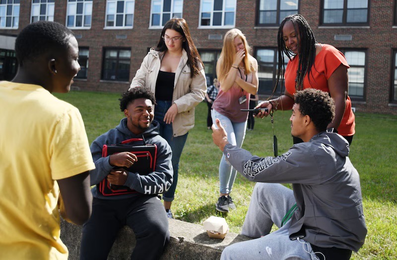 Students and an adult sitting outside having a conversation