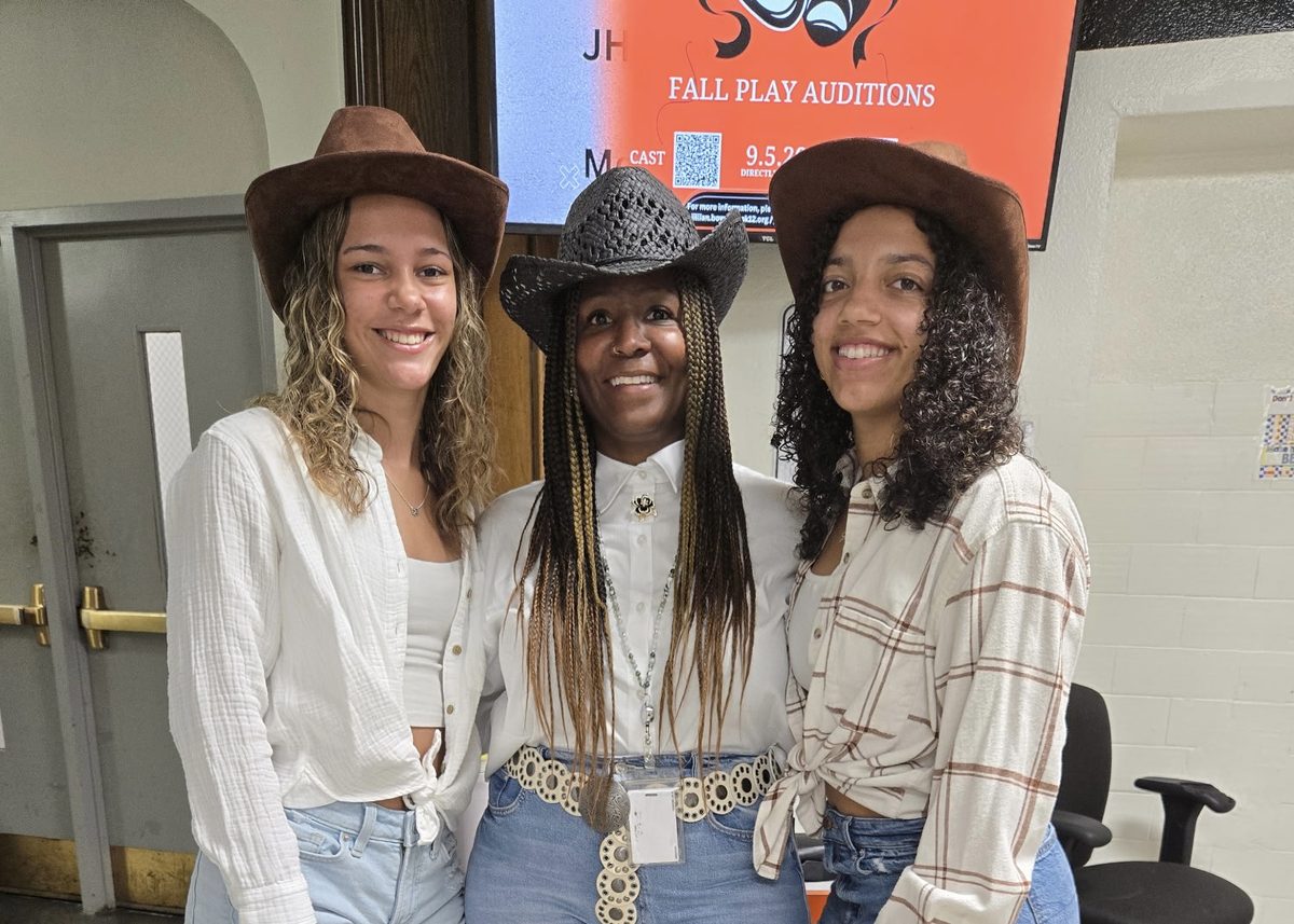 Three students wearing cowboy hats smiling at the camera
