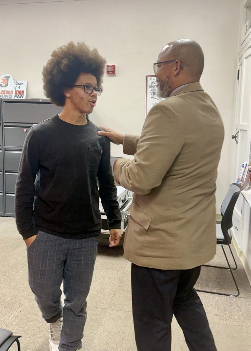 Mr. Lewis talking with a young male student