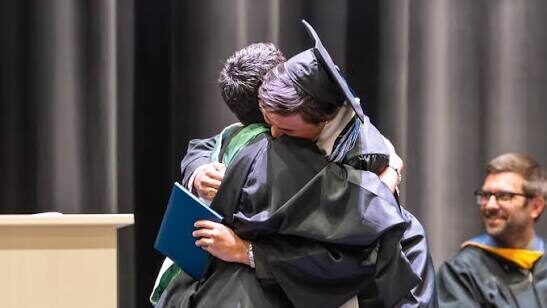student hugging admin during commencement